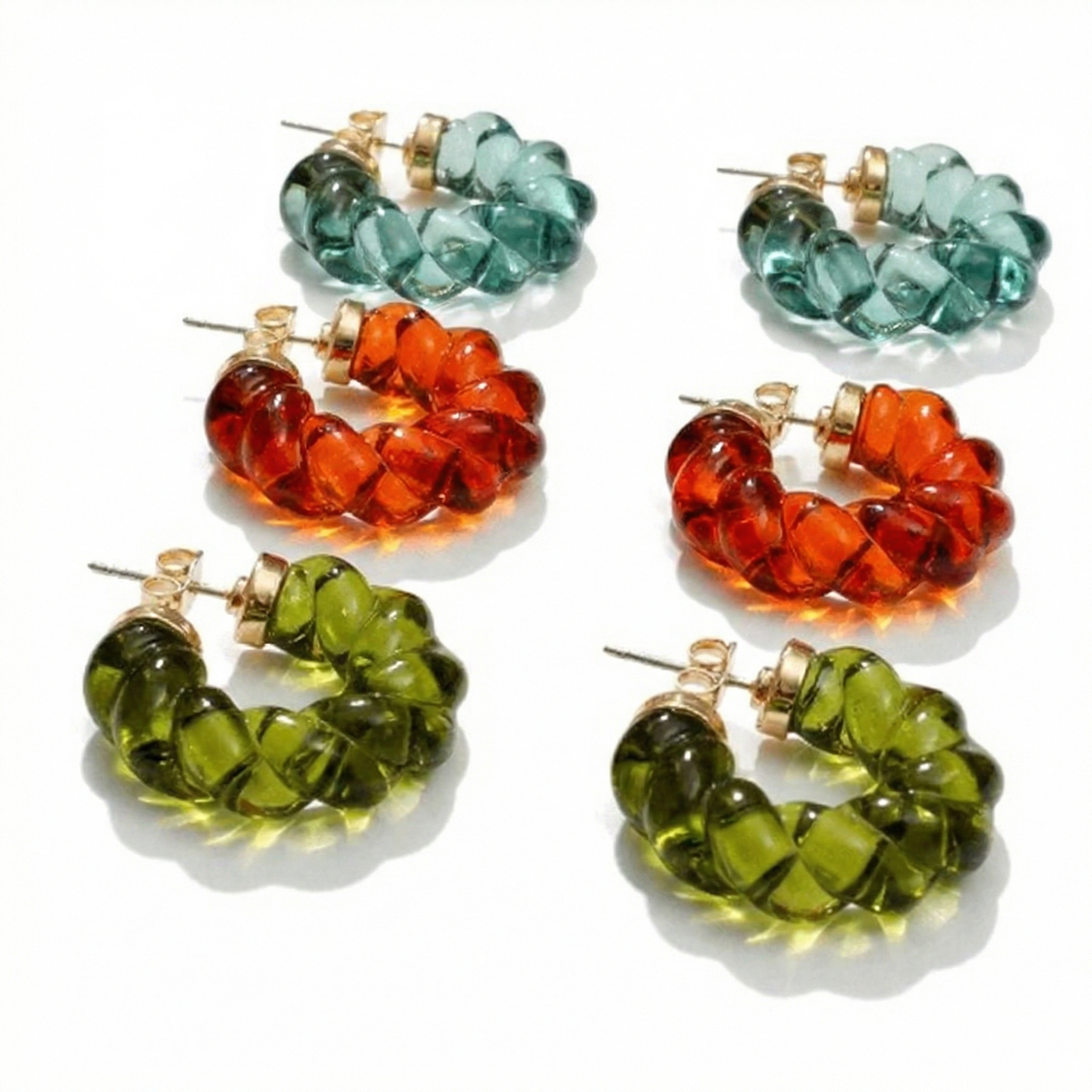 twisted geo hoop earrings with a translucent sculpted design and gold plated stud fastening on a white background.