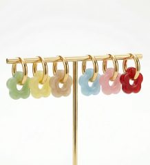 Delicate flower-shaped acrylic hoop earrings in assorted colours on gold-plated stainless steel hoops displayed on a jewellery stand