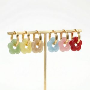 Delicate flower-shaped acrylic hoop earrings in assorted colours on gold-plated stainless steel hoops displayed on a jewellery stand