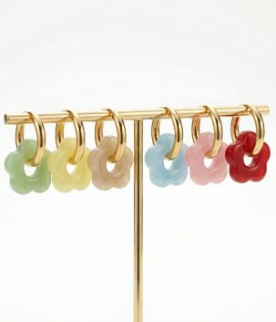Delicate flower-shaped acrylic hoop earrings in assorted colours on gold-plated stainless steel hoops displayed on a jewellery stand