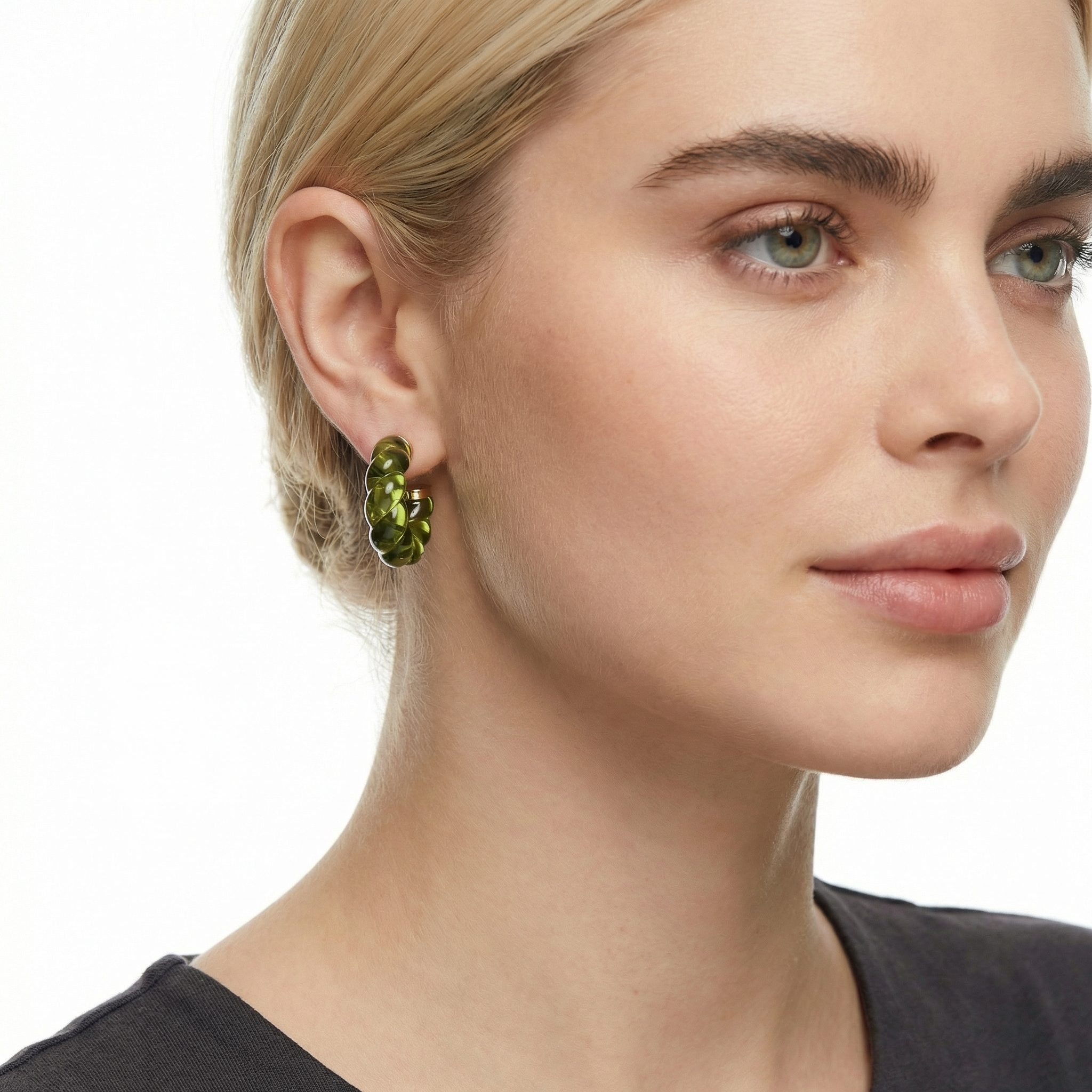 Transparent twisted geometry hoop earrings in olive green with gold-toned electroplated stainless steel studs worn on model