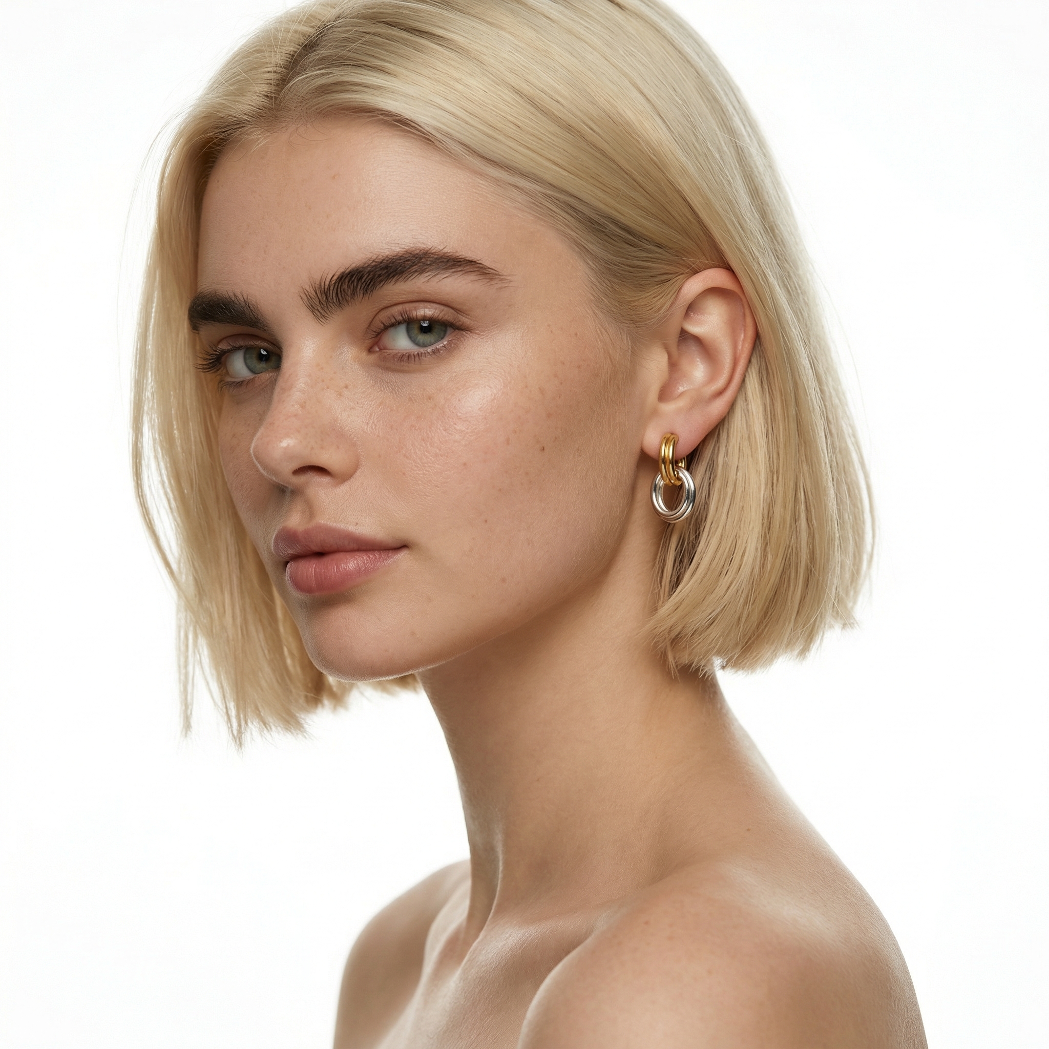 Model wearing interlocking twisted two tone earrings in 18K gold plated and silver titanium steel